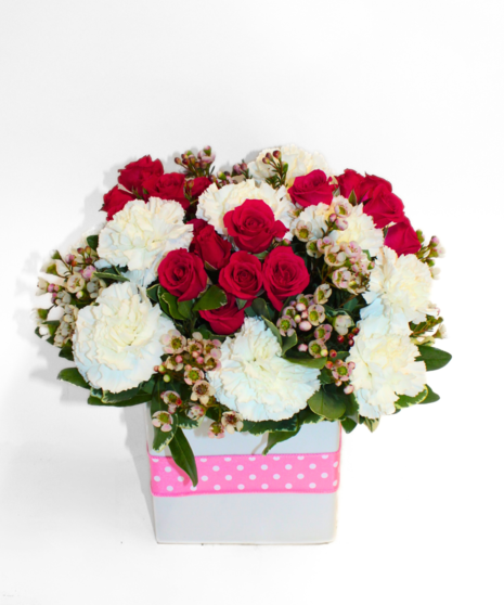 White daisies and pink roses in a pink glass cube tied with a pink and white polka-dot ribbon